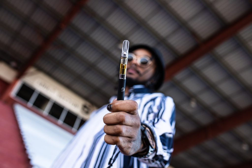 man holding a vape pen close to the camera