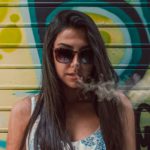 woman in sunglasses exhaling marijuana smoke
