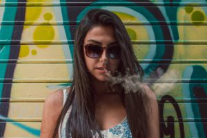woman in sunglasses exhaling marijuana smoke