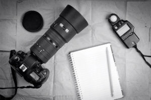 Photography equipment including a professional digital SLR camera and light meter with a blank notebook