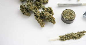 joint with marijuana, Cannabis buds on black table, close up, grinder with fresh weed,