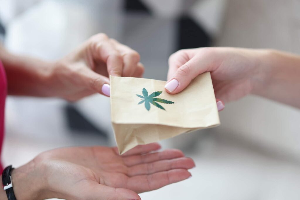 a cannabis delivery in a small bag handed to a person