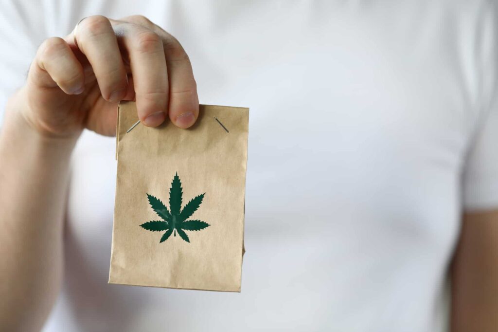 a man holding a small bag of a cannabis delivery